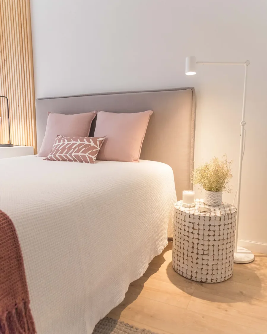 A neatly made white bed in an airy bedroom